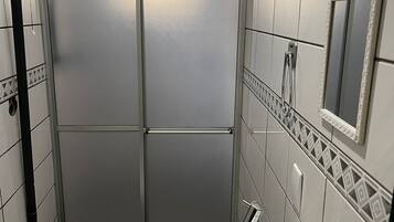 A compact bathroom with a toilet, sink, and shower stall.
