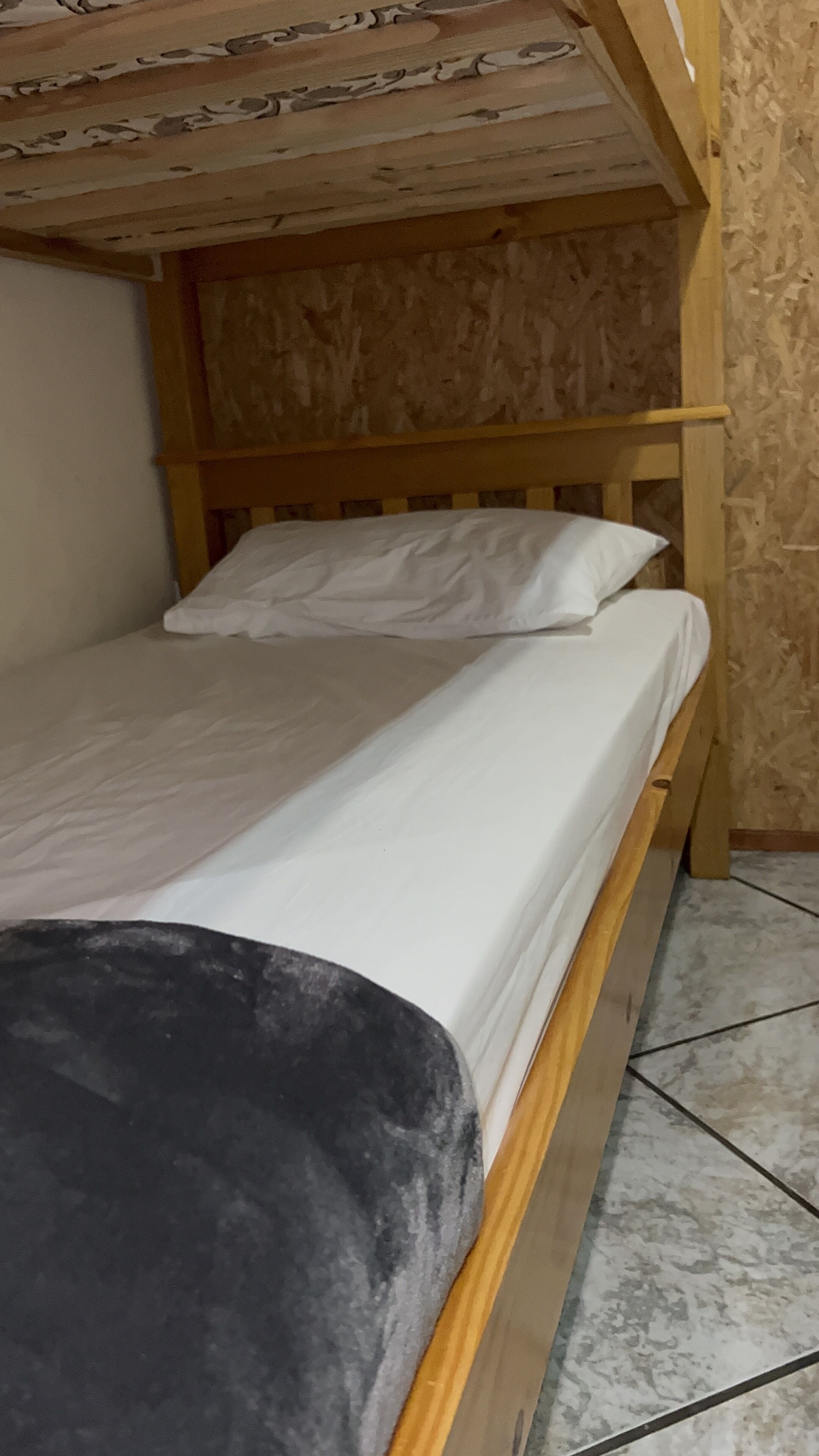 A bunk bed with a wooden headboard and white bedding.