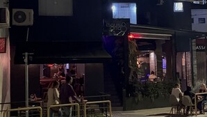 A multi-story building with a ground-level restaurant and a balcony with a decorative plant. - Esquina 8 Hostel (Florianópolis)