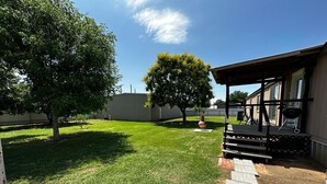 A backyard with a paved patio, a covered seating area, and a lawn.