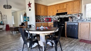 A modern kitchen with wooden cabinets, a dining table with chairs, and a red star decoration on the wall.
