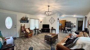 A living room with a sofa, a television, a wooden coffee table, and a chandelier.