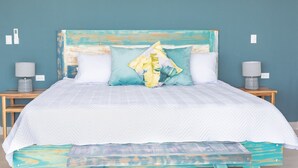 A bed with a white quilt, a blue headboard, and a colorful pillow. There are two bedside tables with lamps. - 🌅 Panoramic Ocean View Penthouse Suite at Villa Costa Vida (Quepos)