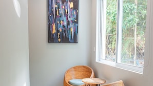 A modern interior with a large window, a painting on the wall, and wicker furniture.