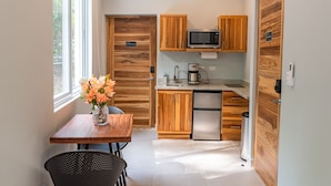 A compact kitchen with wooden cabinetry, a stainless steel refrigerator, a microwave, and a coffee maker.