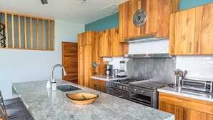 A modern kitchen with wooden cabinets, a marble countertop, a built-in stove, and a coffee maker. - Villa&Tower -17 Bdrms,sleeps 55-AC,Elevator,Pool (Quepos)