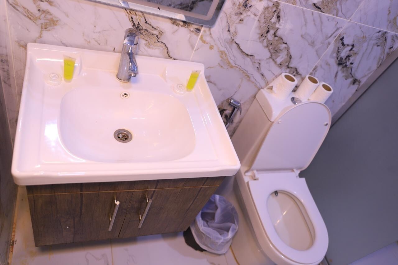 Ein Badezimmer mit Waschbecken, Holzkabinent und Toilette.