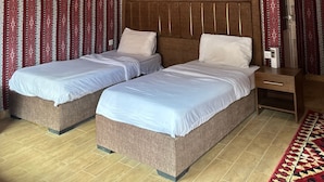 Une chambre avec deux lits, un plafond en bois, des rideaux à motifs et un appareil de climatisation.