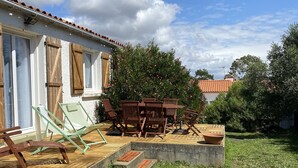 Une terrasse avec des meubles en bois, une marche en béton et une cour gazonnée.