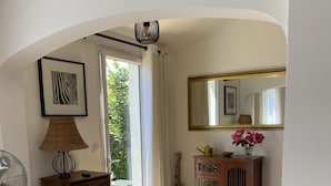Une pièce avec un plancher en bois, un tapis orné du drapeau britannique, un ventilateur, un meuble à bouteilles, un miroir et un buffet en bois agrémenté d’objets décoratifs.