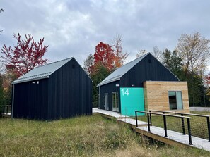 Two modern buildings with a metal roof, one with a number '14' sign, and a wooden structure adjacent to them.