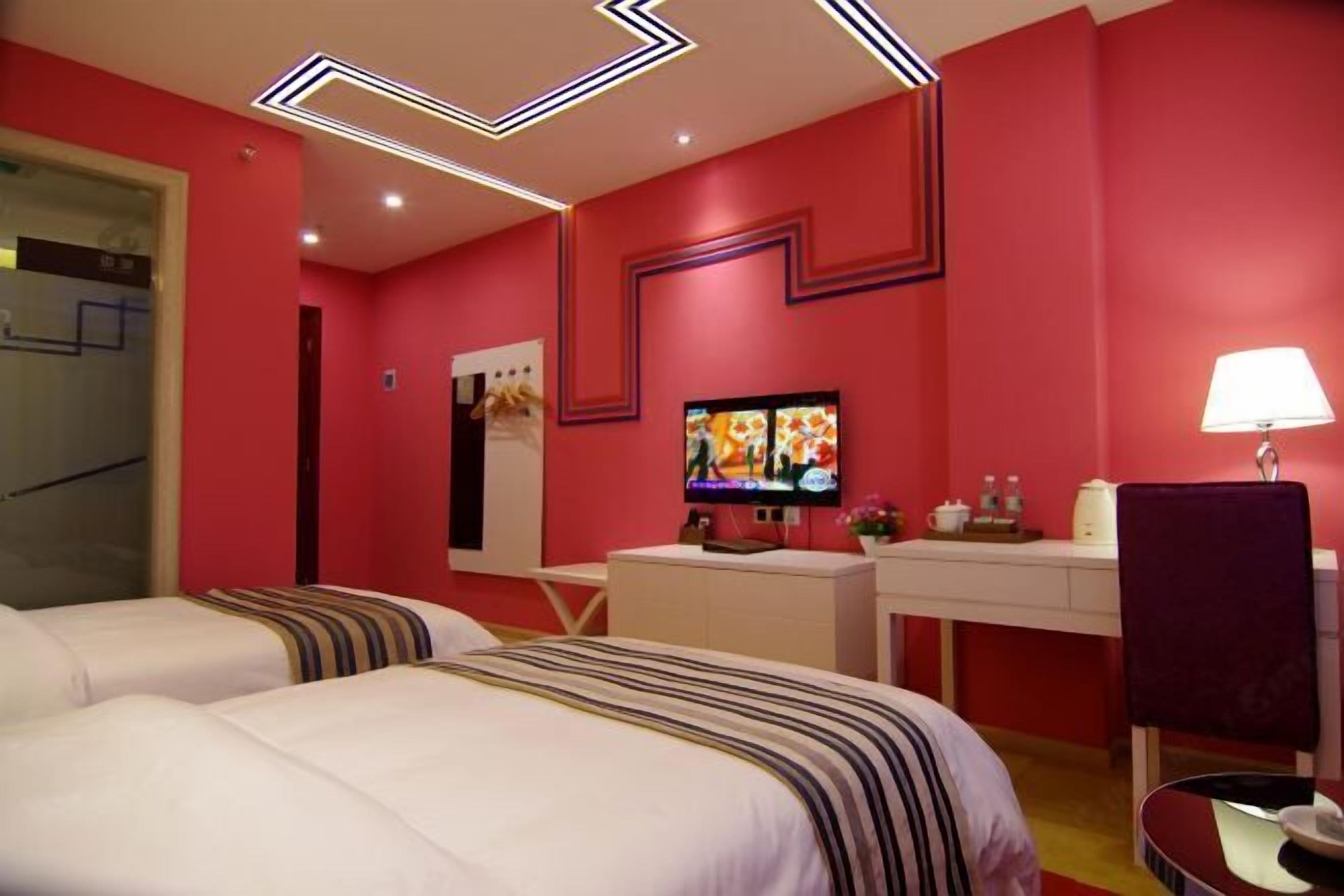 A hotel room with two beds, a desk, a TV, and a chair.