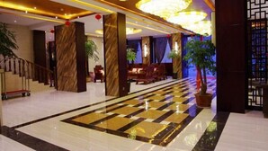 A hotel lobby with a checkered floor, marble pillars, and a staircase. - Biancheng Hotel (Ruili)