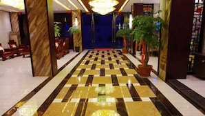 A hotel lobby with a checkered floor, marble columns, and a chandelier. - Biancheng Hotel (Ruili)