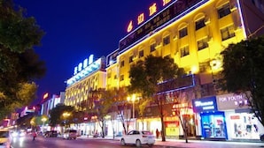 A brightly lit hotel with multiple floors and a prominent sign on the top. - Biancheng Hotel (Ruili)