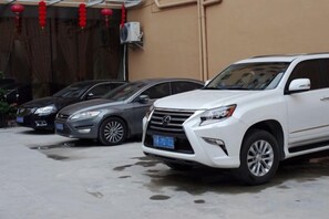 A parking area with three vehicles, including a white SUV and two black sedans.