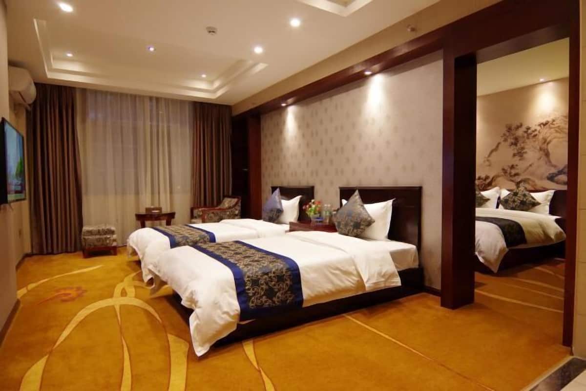 A hotel room with two beds, a large mirror, and a carpeted floor.