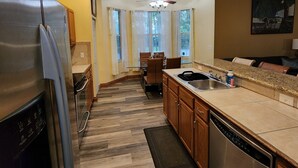 A modern kitchen with a stainless steel refrigerator, wooden cabinets, a granite countertop, and a dishwasher.