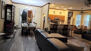 A modern living room with a sofa, dining table, and kitchen area.