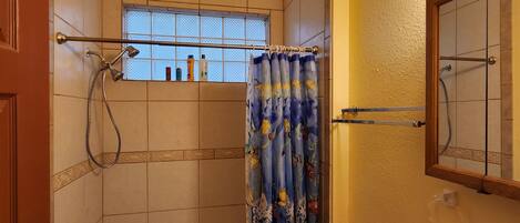 A bathroom with a bathtub, toilet, and sink. There is a window with a view of the outside, a shower curtain, and a towel rack.