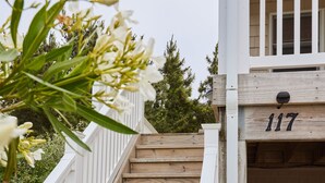 A wooden staircase with white railings leading to a building with the number 117. - New! Refreshed modern coastal retreat in Duck! (Kitty Hawk)
