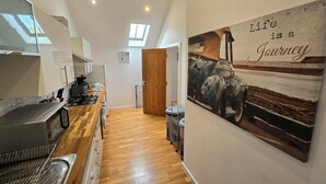 Une cuisine moderne avec un plancher en bois, une cuisinière encastrée et une grande fenêtre.