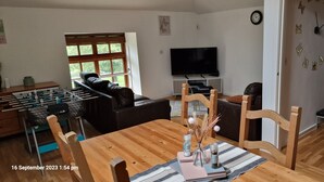 Un salon avec un canapé, une table à manger en bois et un téléviseur.