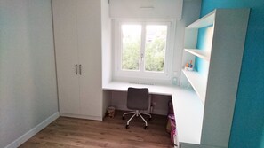 Et værelse med skrivebord, stol og reoler.