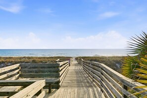 A wooden boardwalk leading to the beach with a clear view of the ocean.