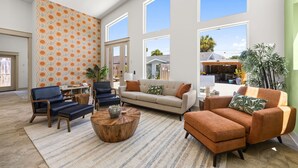 A spacious living room with a large window, a patterned wall, and a variety of seating options. - 2 Homes 1 Incredible Stay*Private Pool & 5 Kings! (Panama City Beach)