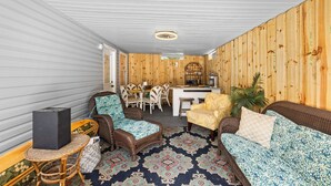A covered patio with wicker furniture, a dining table, and a kitchen area.