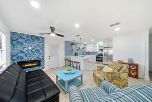A modern living room with a fireplace, a sofa, a coffee table, and a patterned armchair.