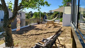 A backyard with a hammock, a wooden swing, and a wooden bench.