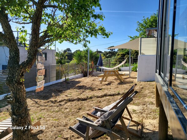 A backyard with a hammock, a wooden swing, and a wooden bench.