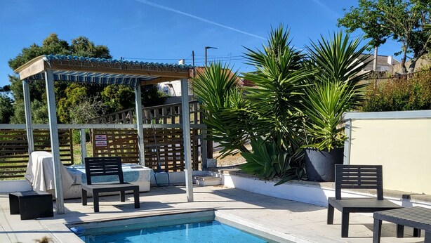 A swimming pool with lounge chairs and a covered seating area.
