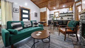 A cozy living room with a green sofa, a coffee table, and a fireplace.