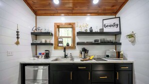 A modern kitchen with black cabinets, stainless steel appliances, and decorative items on shelves.