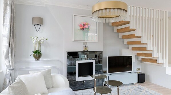 Relax in a stylish living space with a sofa, flat-screen TV, and contemporary chandelier.