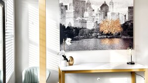 A modern room with a cityscape painting, a desk with a vase and a lamp, and a chair. - Charming updated LOFT style townhouse!!! (Midvale)