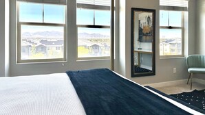 A bedroom with a large bed, two windows with blinds, a chair, and a framed picture on the wall. - Charming updated LOFT style townhouse!!! (Midvale)