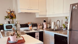A modern kitchen with white cabinets, a stainless steel refrigerator, a microwave, and a dishwasher. - WorldCup Central- Easy access for sports and entertainment. (Houston)