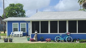 Une maison bleue avec un porche couvert, un banc blanc et un vélo bleu.