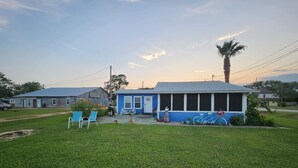Une maison bleue avec un porche, une pelouse et un vélo.