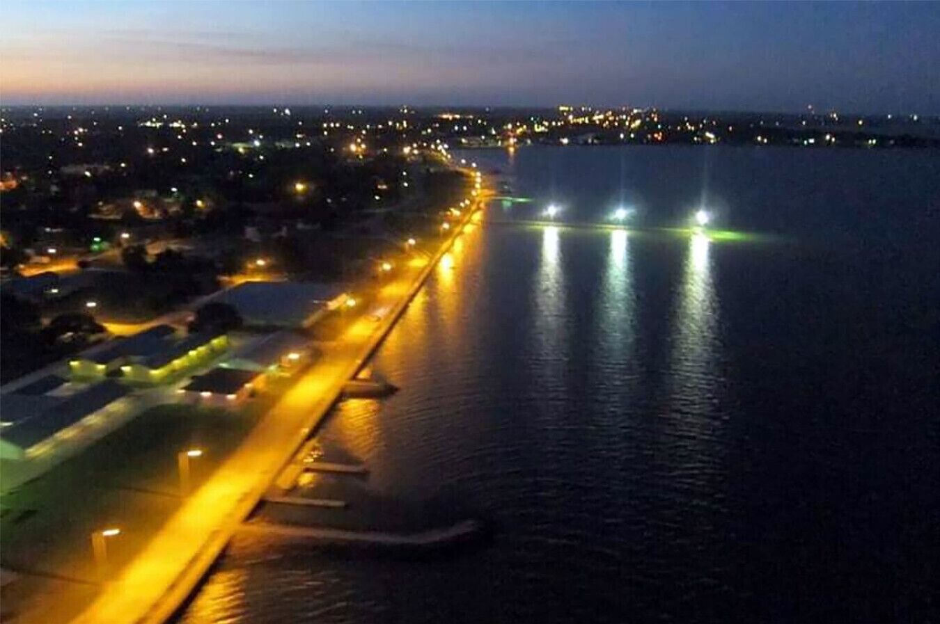Una zona costera con una carretera que bordea el agua, iluminada por farolas.