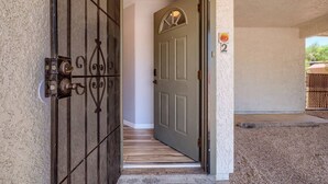 Una puerta que da a un pasillo con piso de madera y una puerta cerrada con el número 2.