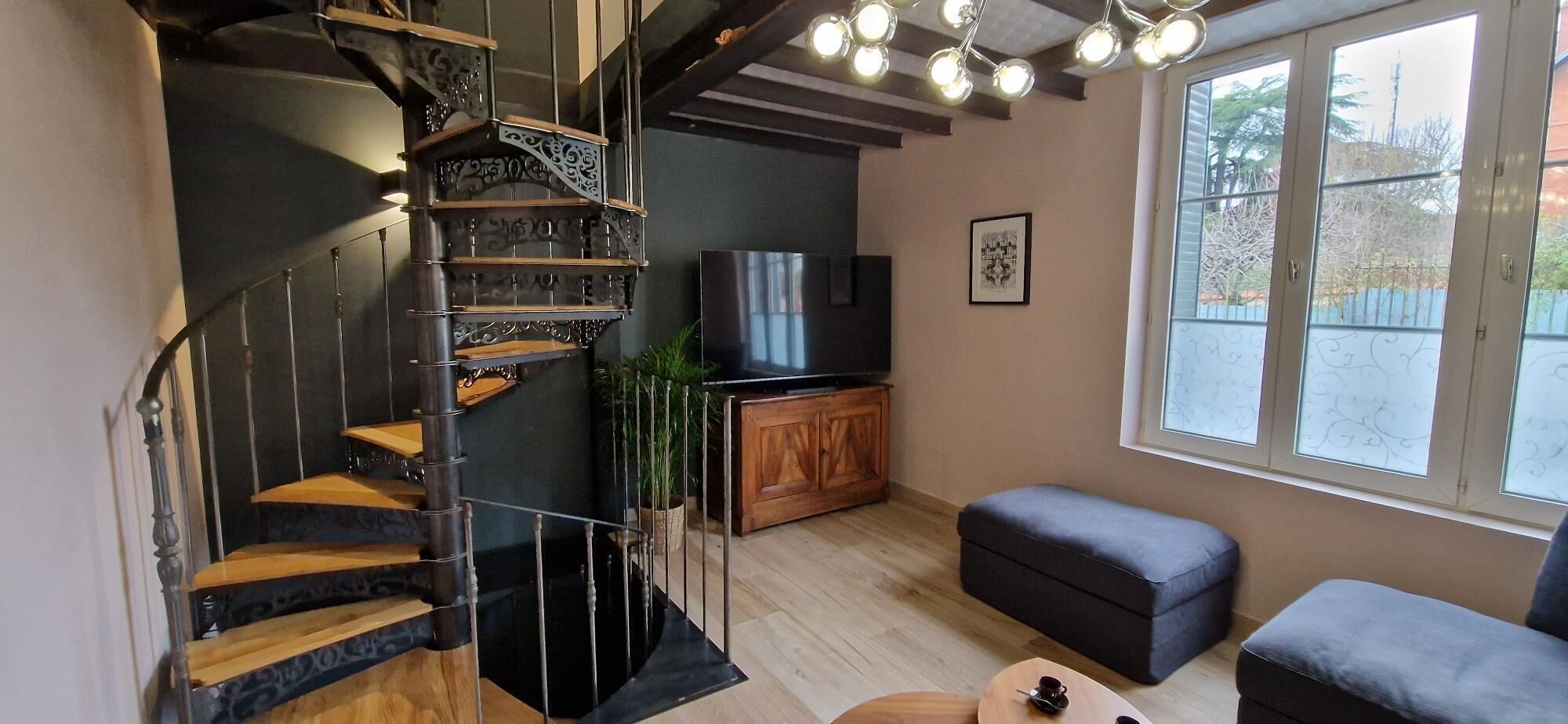 Een modern interieur met een wenteltrap, een flatscreen televisie, een houten kast en een raam met uitzicht.