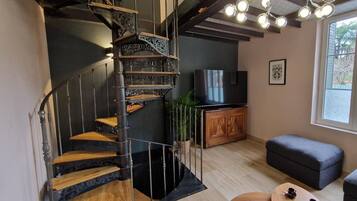 Een modern interieur met een wenteltrap, een flatscreen televisie, een houten kast en een raam met uitzicht.