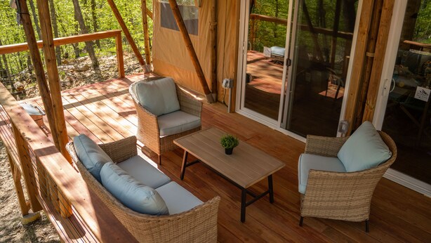 Een houten terras met rieten meubels, een tafel en een plant in pot.