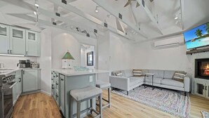 A modern kitchen with white cabinets, a bar area, and a seating area with a sofa and a fireplace. - Charming Downtown Cottage w/ Modern Amenities (Coeur d'Alene)