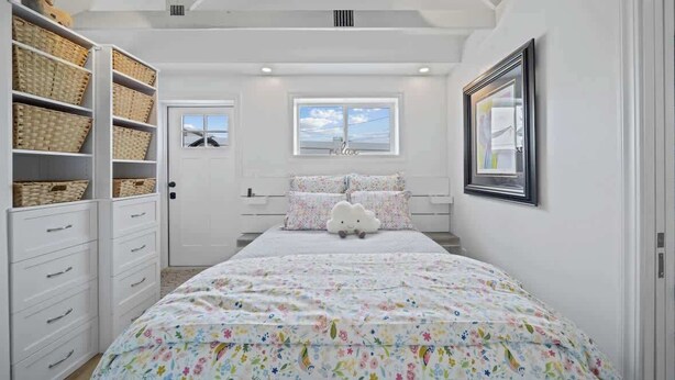 Ein Schlafzimmer mit Bett, Fenster, Kleiderschrank und einem gerahmten Bild an der Wand.